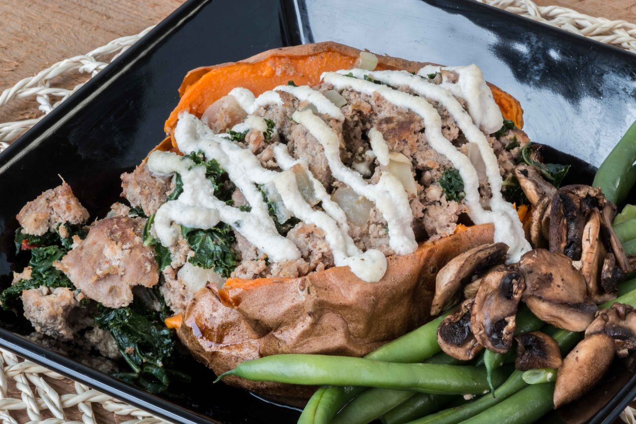 Delicious stuffed sweet potato with green beans and mushrooms topped with creamy sauce.